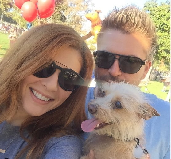 Picture of Rachelle Lefevre posing for a photoshoot with her husband and her dog wearing sunglasses